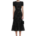 Woman wearing a black patterned dress on a white background